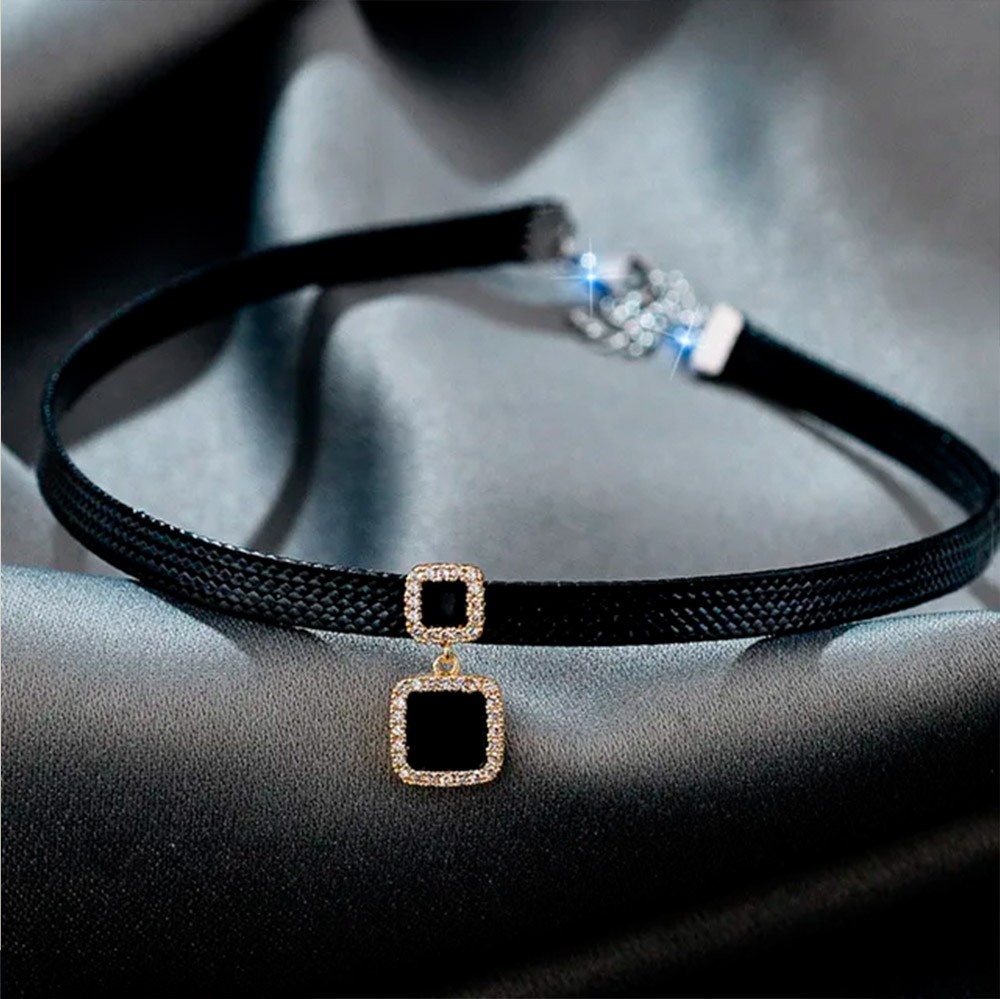Coleira Social Choker Preta com Corrente e Pingente Quadrado, vista em �ngulo sobre tecido sedoso, mostrando detalhes da corrente