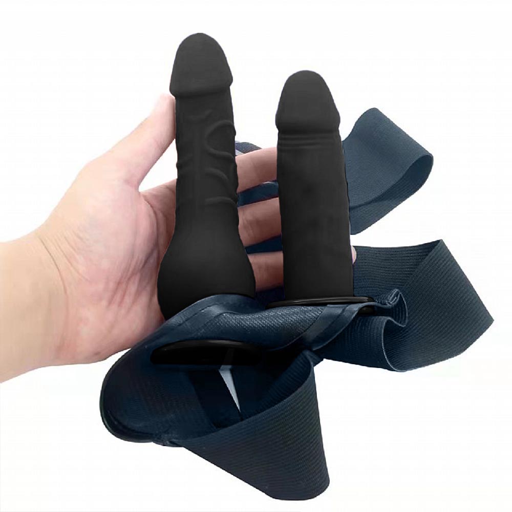 Detalhe dos dois p�nis real�sticos pretos de silicone em uma m�o, mostrando a textura e o encaixe na cinta