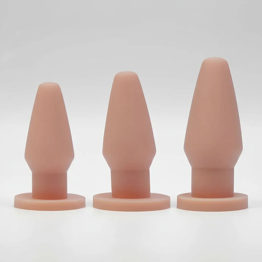 Vis�o frontal dos tr�s plugs anais bege, destacando a textura suave e o formato c�nico progressivo, em fundo claro