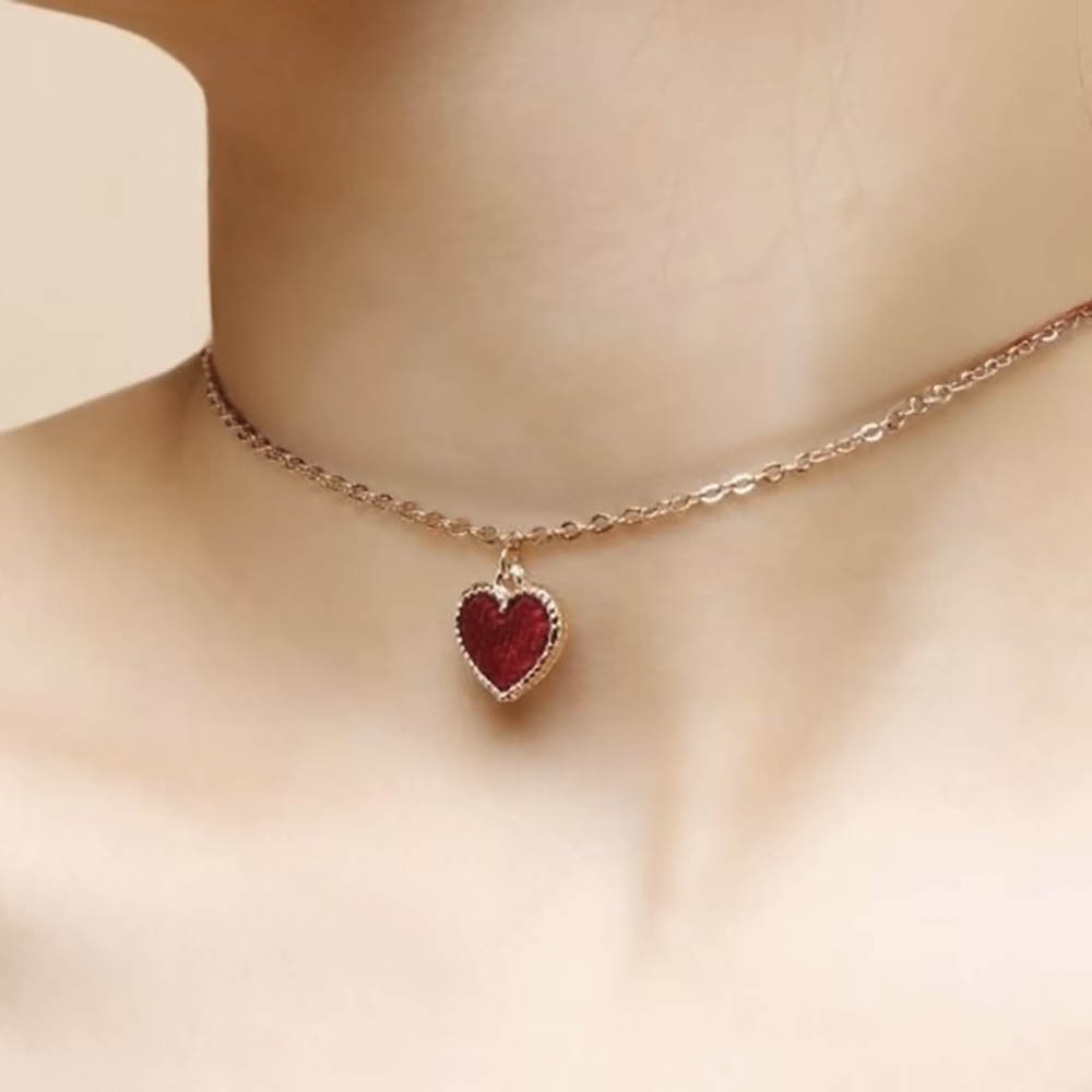 Colar sensual dourado com pingente de cora��o em vista pr�xima, destacando a corrente fina e o detalhe do fecho