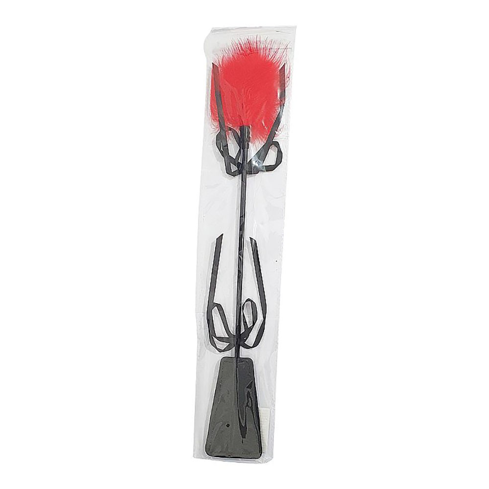 Close-up da p� de PU preto da chibata com plumas vermelhas, destacando a textura do material e o la�o decorativo.
