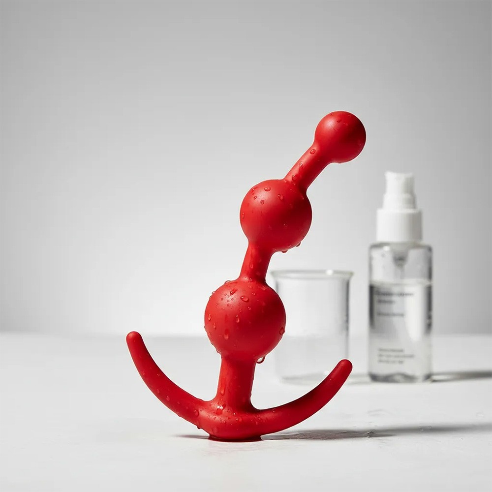 Plug anal massageador Balls em silicone vermelho - foto ambientada com gotas d'agua, destacando a capacidade de ser usado em banho