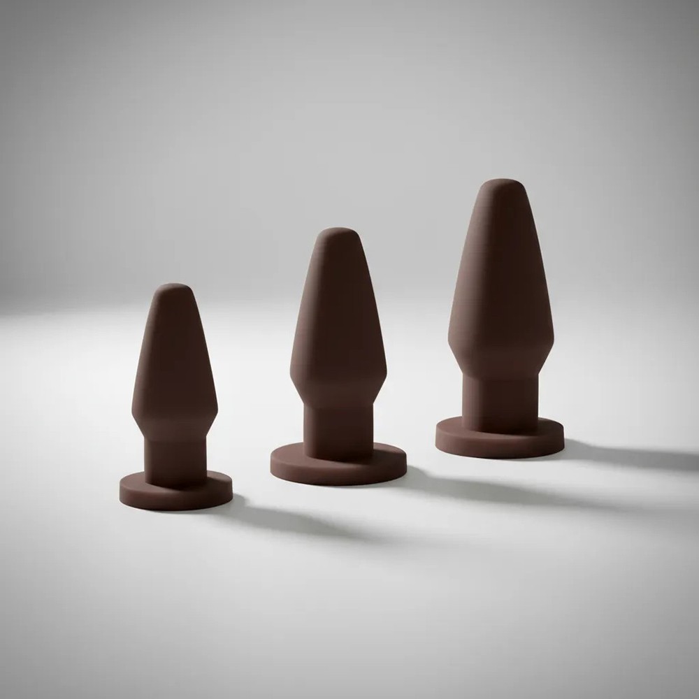 Kit de plugs anais marrons em PVC flex�vel, vista lateral em ambiente neutro, mostrando os tr�s tamanhos progressivos