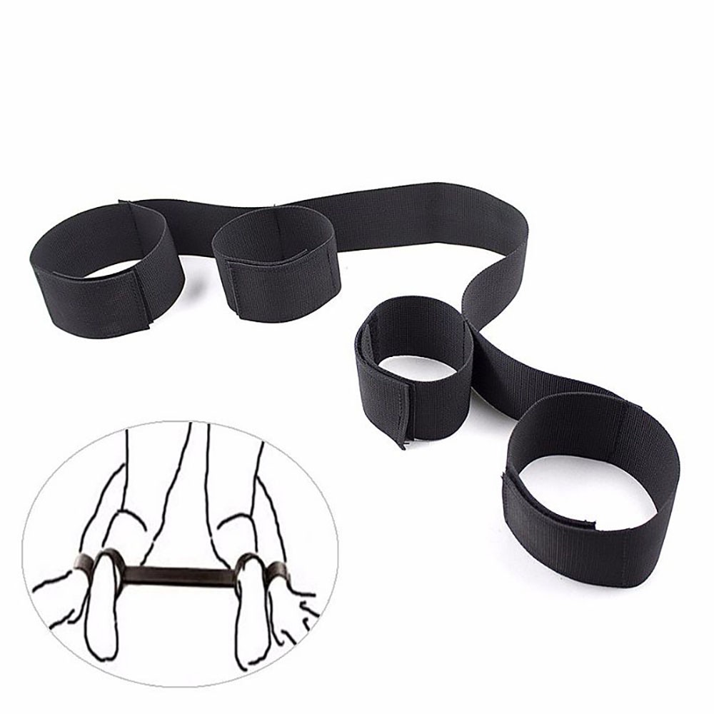 Separador de pernas em nylon preto, modelo com os pulsos algemados na frente, mostrando as algemas ajust�veis e o velcro