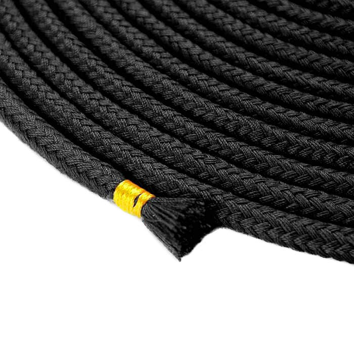 Close-up da corda de algod�o preta para bondage e shibari, mostrando a textura tran�ada e o detalhe do acabamento amarelo na ponta