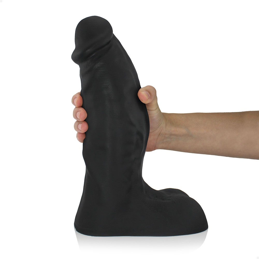 P�nis gigante e grosso flex�vel com escroto preto, sendo segurado por uma m�o, destacando o tamanho real