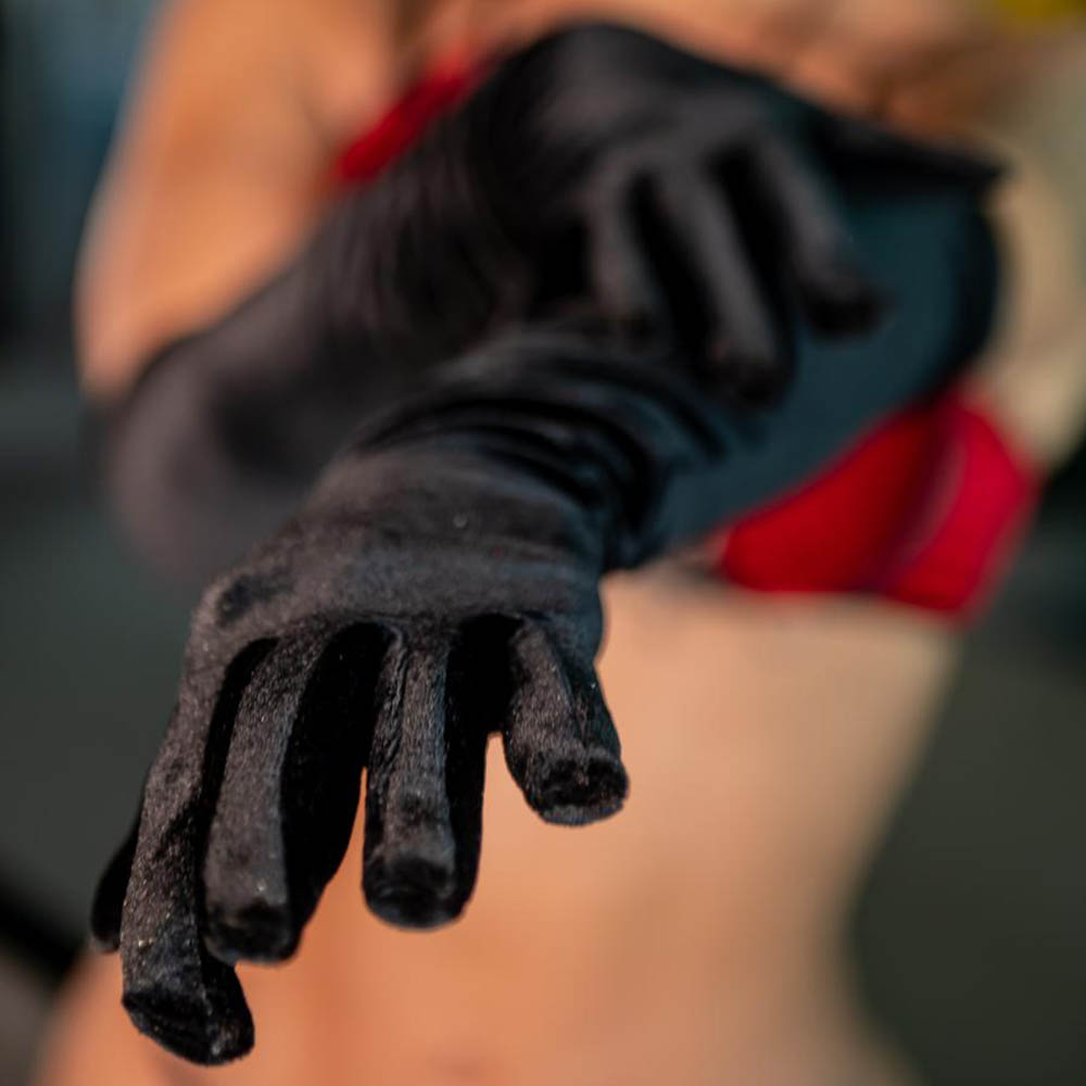 Vis�o frontal do par de luvas em veludo preto 7/8 sendo usado, com uma m�o estendida, mostrando o caimento perfeito do tecido