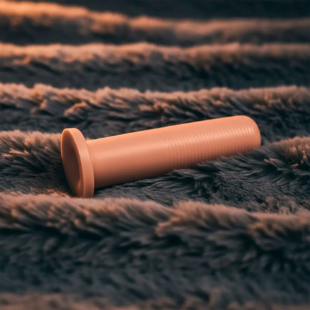 Plug anal KCT flex�vel bege sobre uma superf�cie de pelo macio, mostrando sua base de seguran�a e o corpo alongado