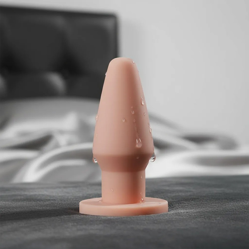 Plug anal bege de PVC flex�vel visto por cima, mostrando o topo c�nico e a transi��o para a base