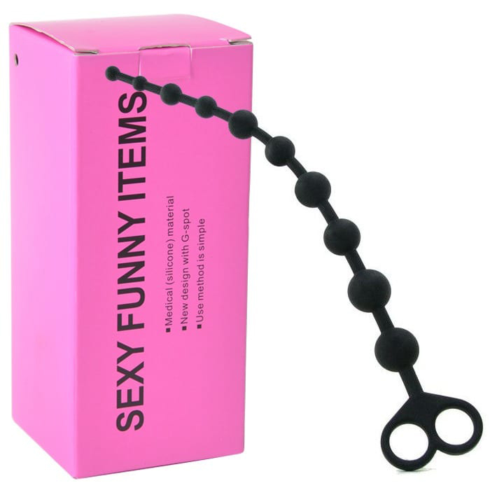 Detalhe do Conjunto de Bolinhas Anais em Silicone Preto ao lado da embalagem rosa, mostrando o contraste e o design do produto