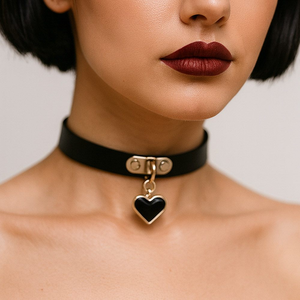 Close no pesco�o de uma modelo usando a coleira choker preta com pingente de cora��o dourado e esmaltado, evidenciando o estilo minimalista e sexy
