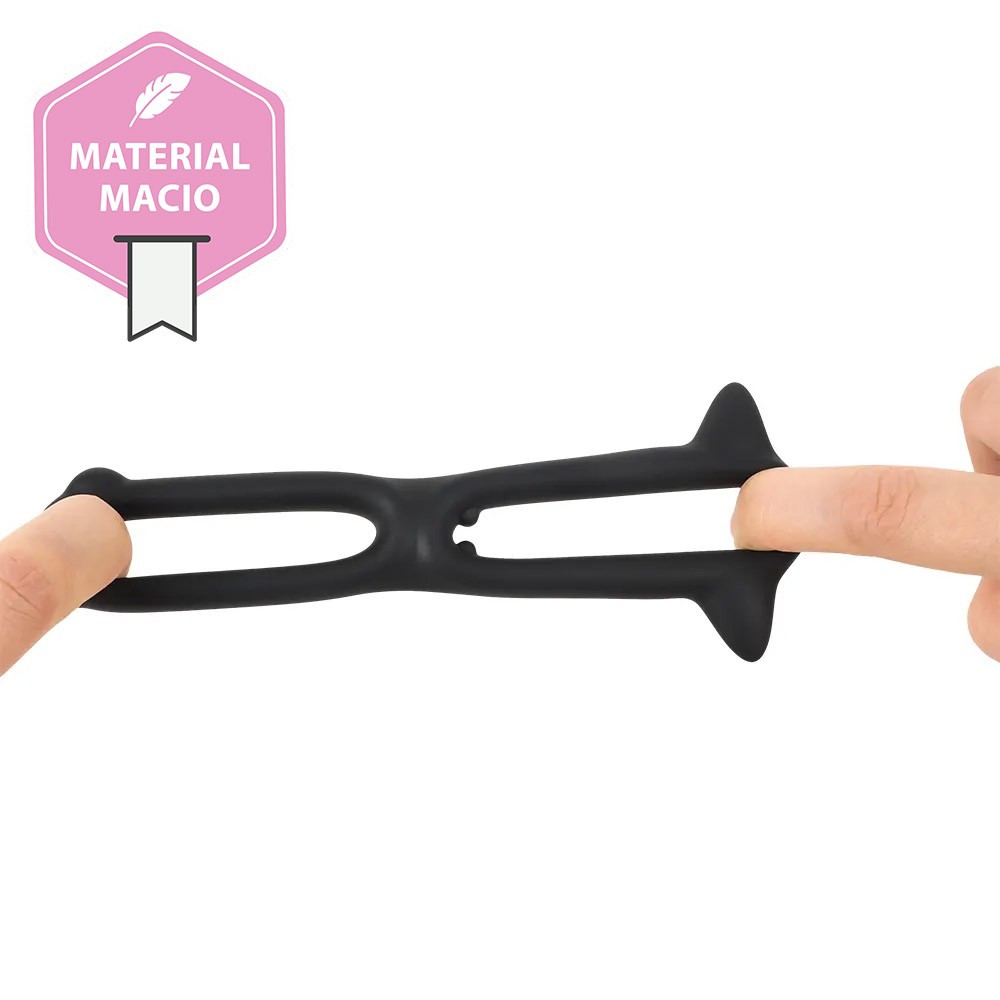 Anel Peniano e Escrotal Toran Preto em silicone, sendo esticado para demonstrar a flexibilidade do material, com selo 'MATERIAL MACIO'.
