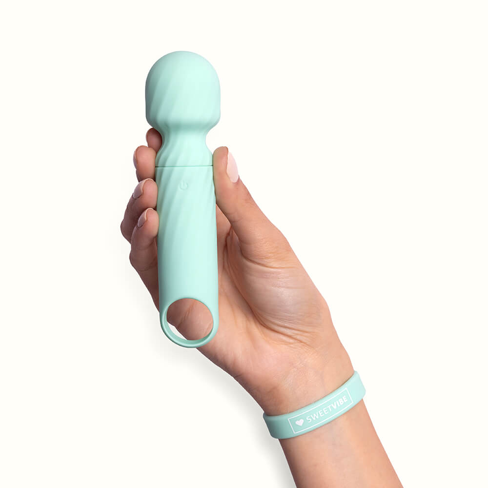 Massageador Er�tico Dengo Verde em uso, na m�o de uma mulher, com a pulseira Sweetvibe no pulso