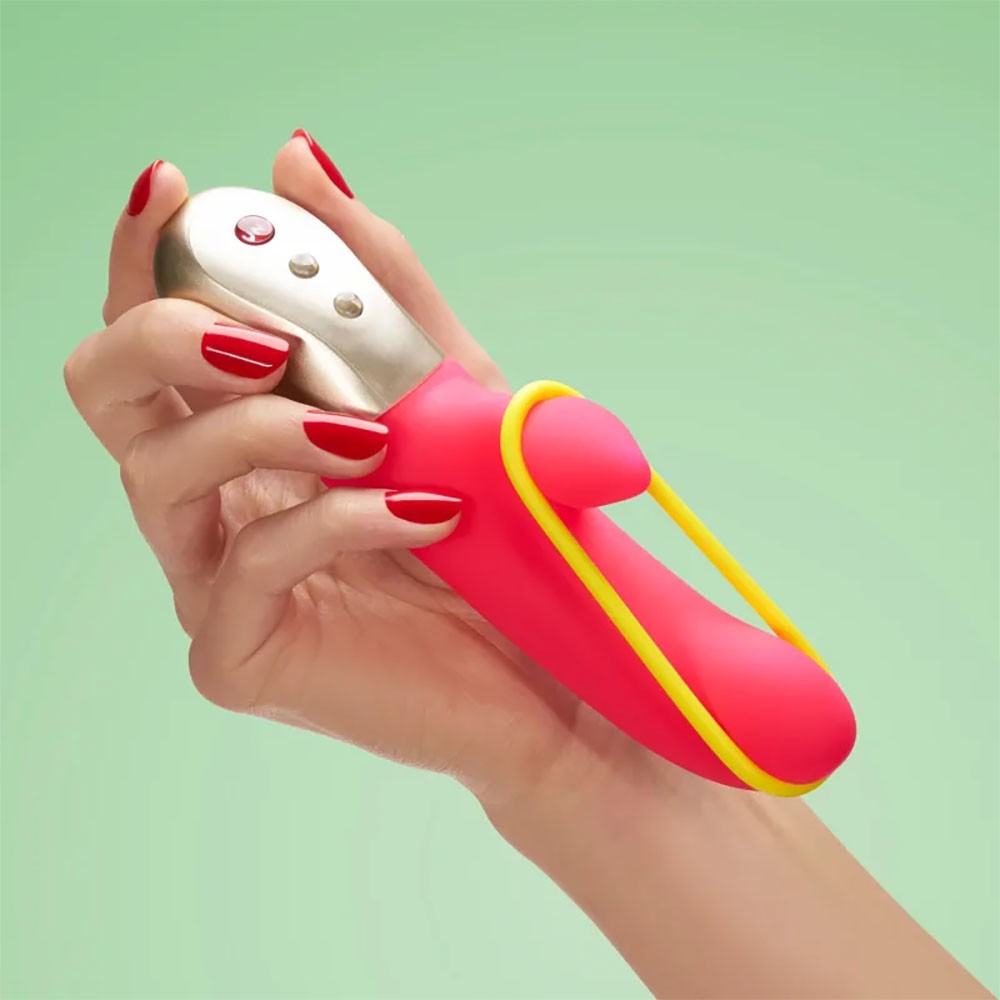 Vibrador Duplo em Silicone Recarreg�vel 6 Modos de Vibra��o Amorino Pink em uma m�o feminina, destacando o design ergon�mico, a cor pink do silicone e o bra�o externo amarelo