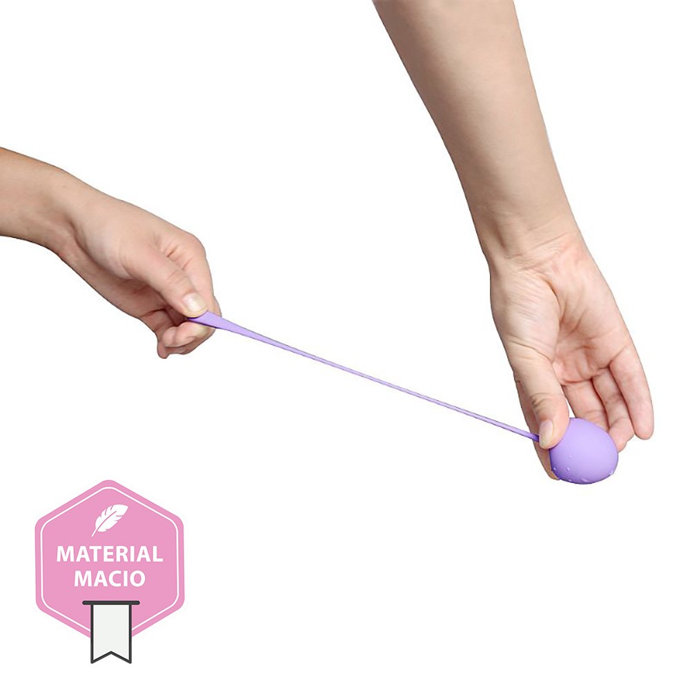 M�os segurando uma Kegel Ball de silicone lil�s, demonstrando o material macio e a haste de remo��o